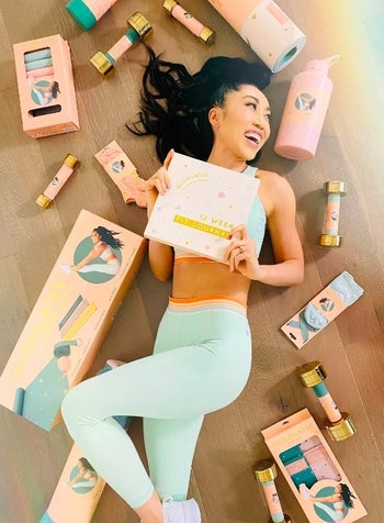 Model laying on ground surrounded by blogilates exercise equipment
