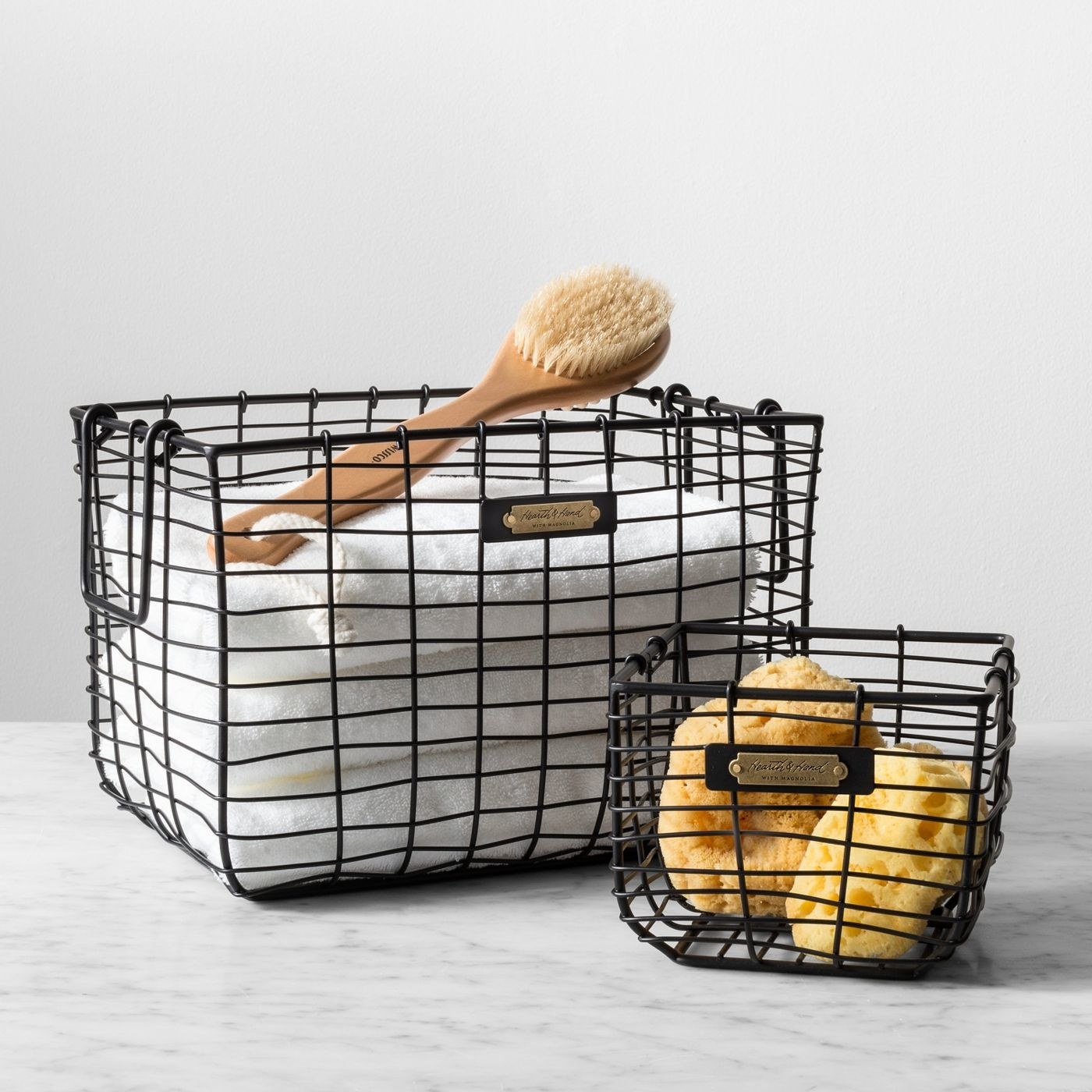 two black wire storage baskets with bath products inside