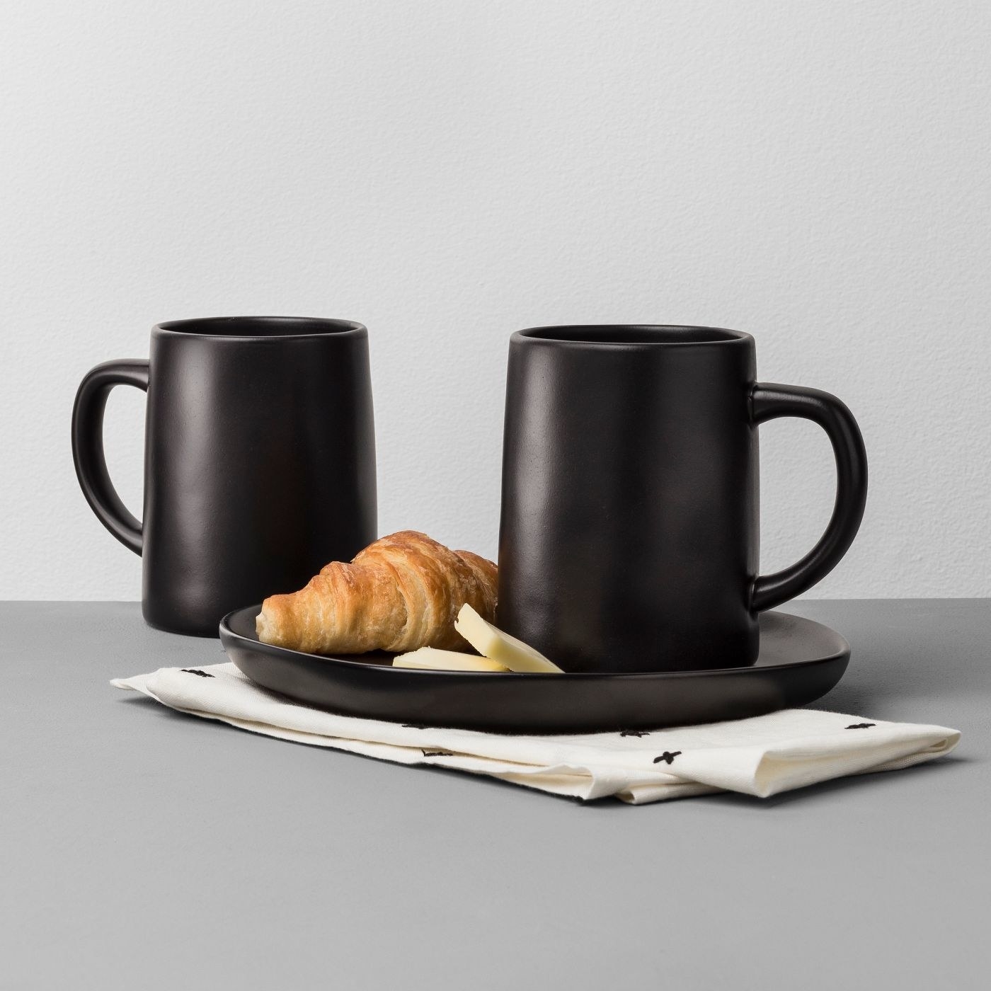 two black stoneware mugs on a table