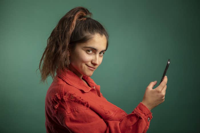 A person holding a phone up and smirking