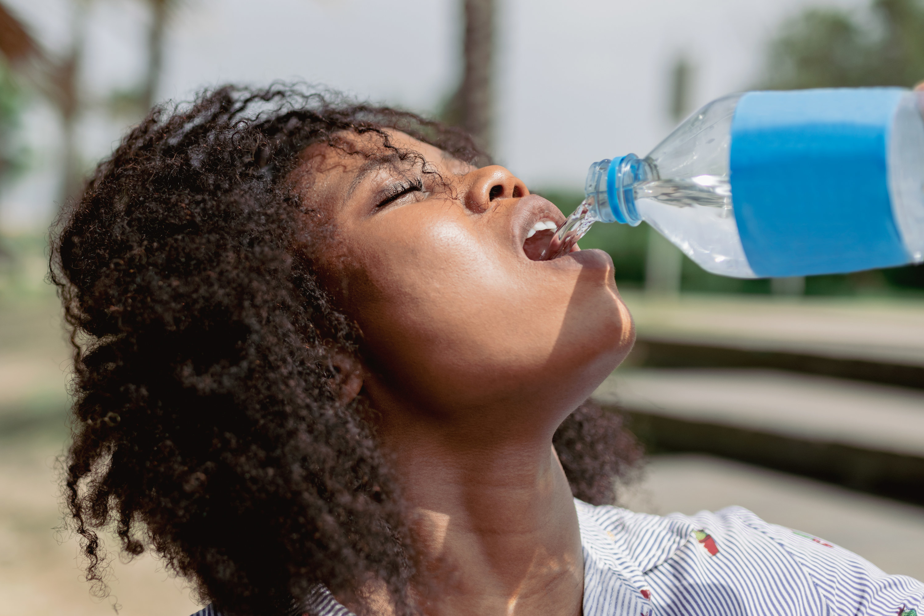 A person drinking from a half-full bottle of water