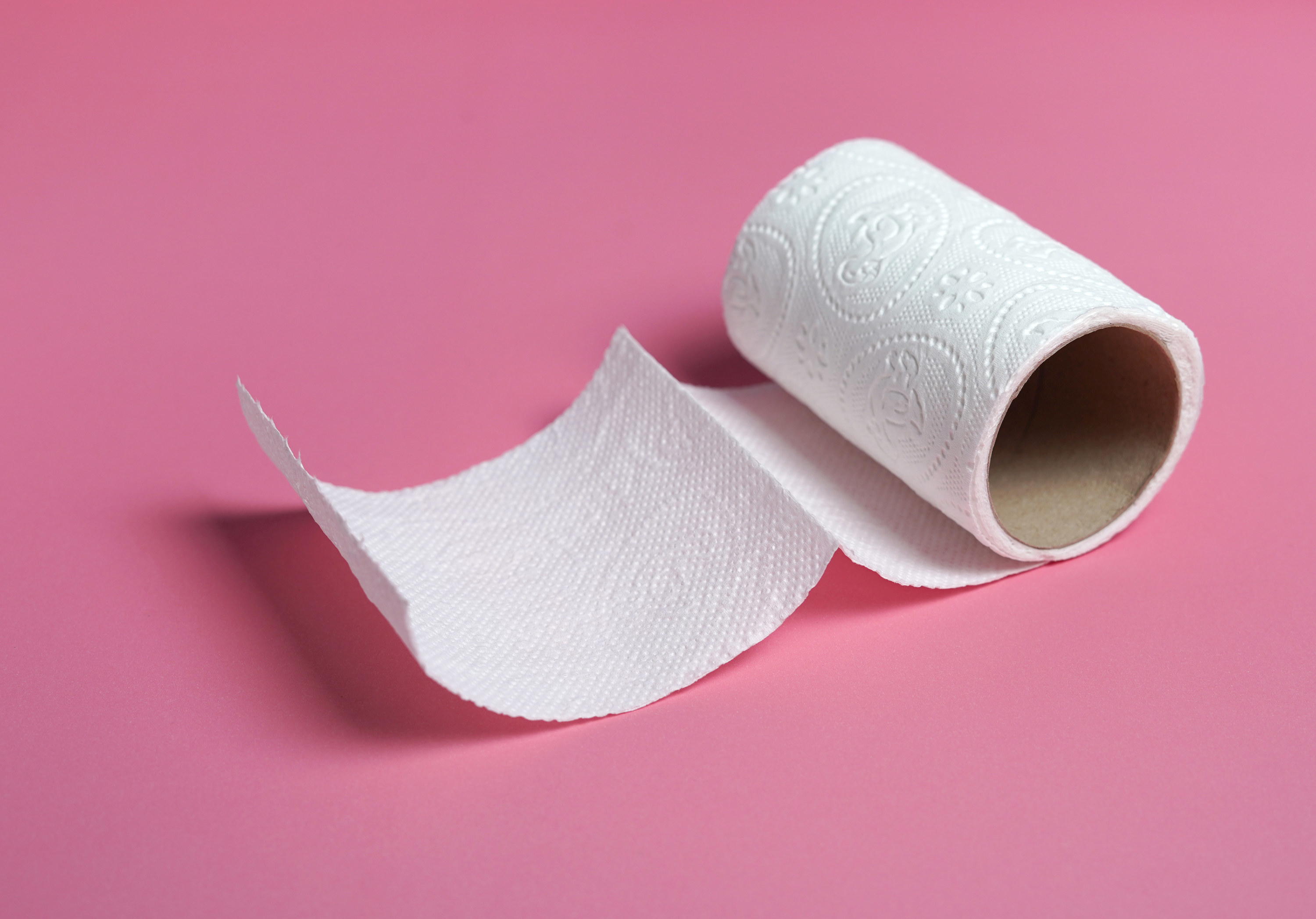Toilet paper roll near the end of its life on a colored background