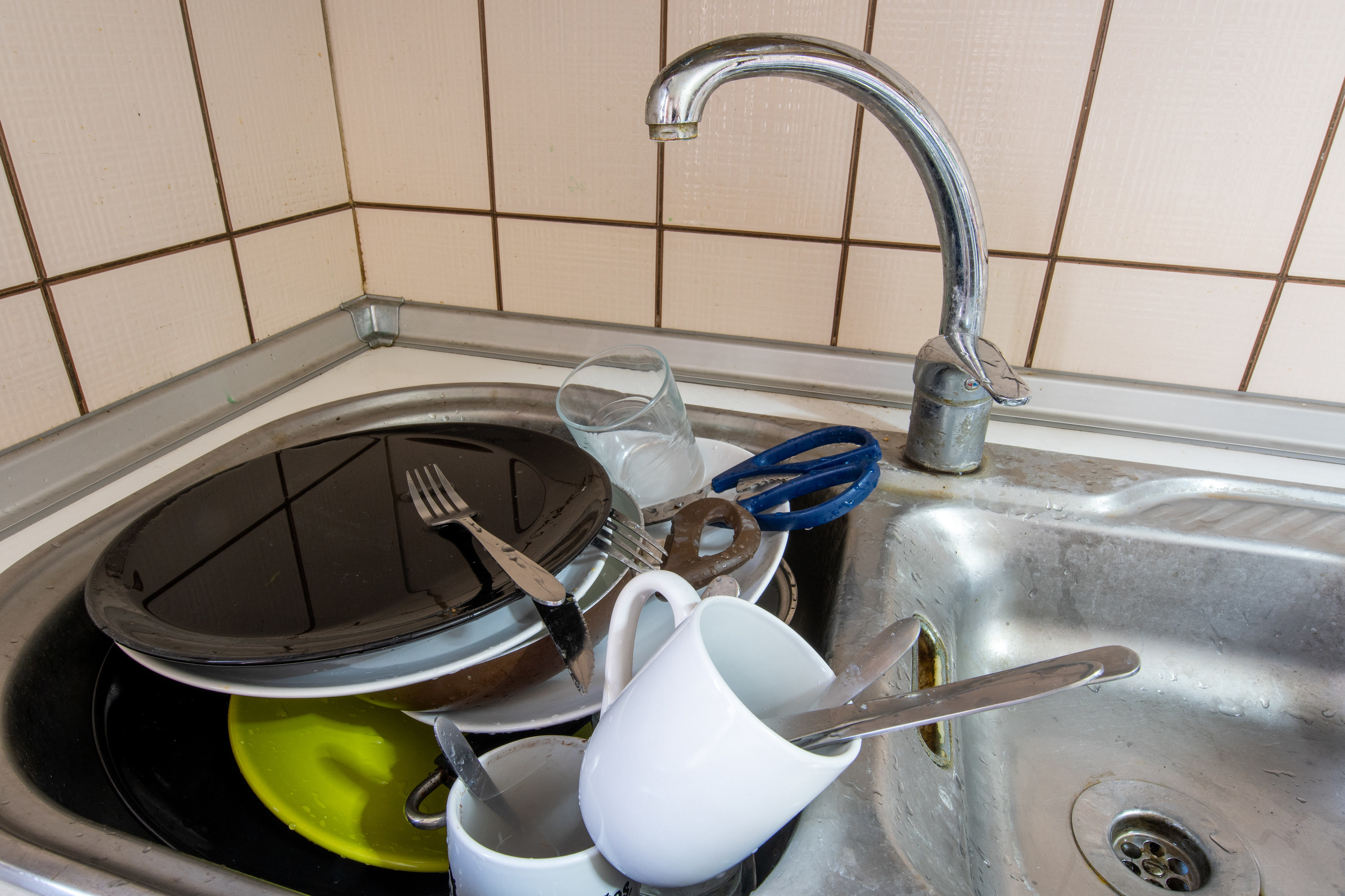 Dishes piled high in a sink