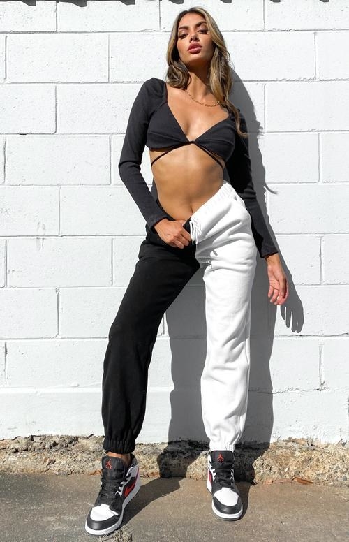 model wearing a crop top and sweatpants with one black leg and one white leg