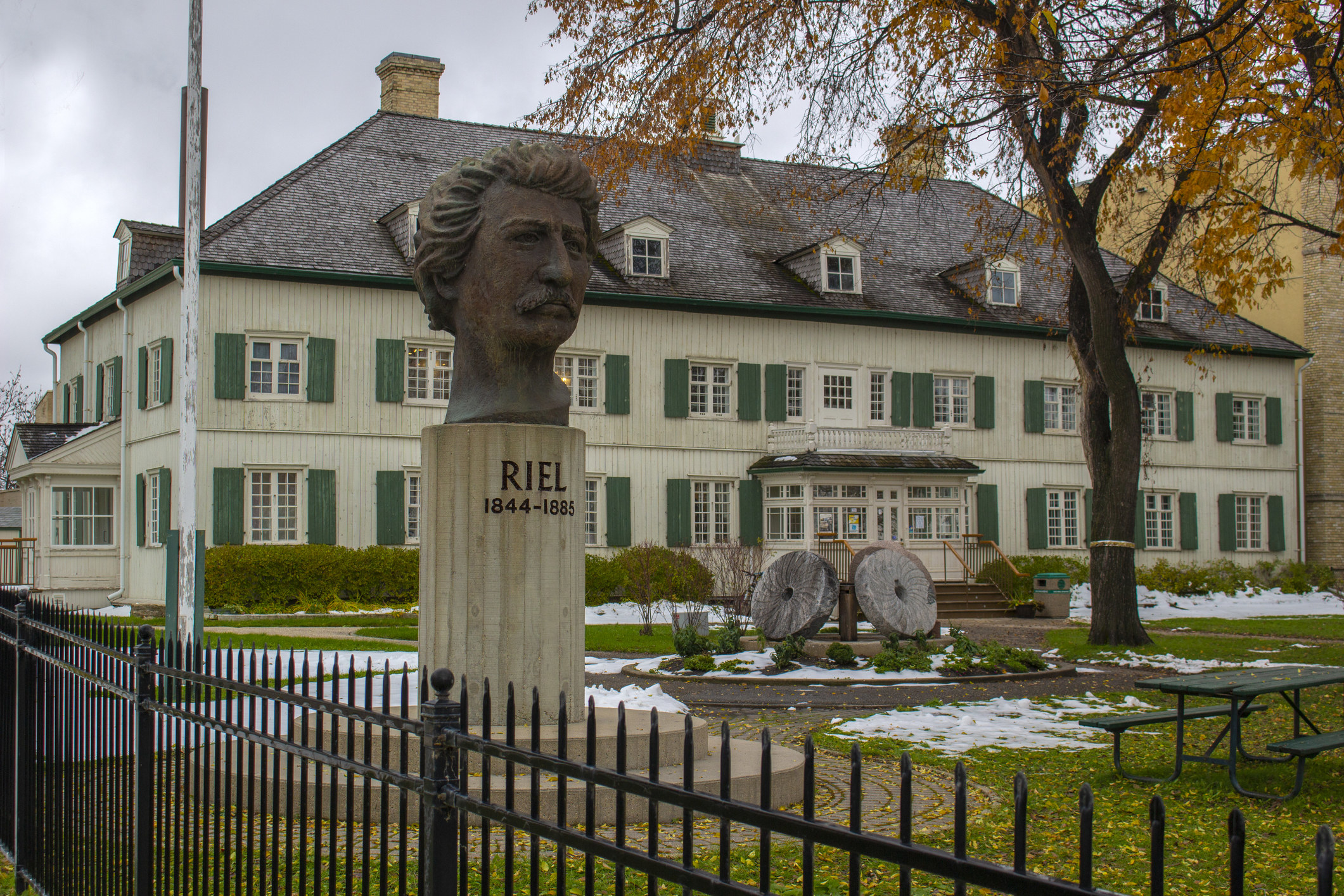 the saint boniface museum in the fall with a bust of riel in the foreground