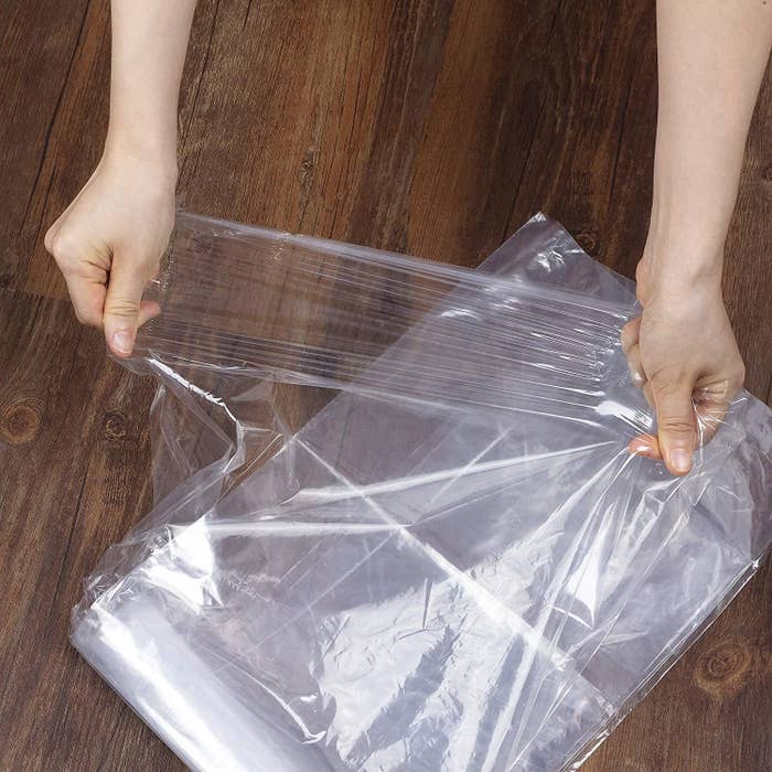 person unfolding thin plastic tarp
