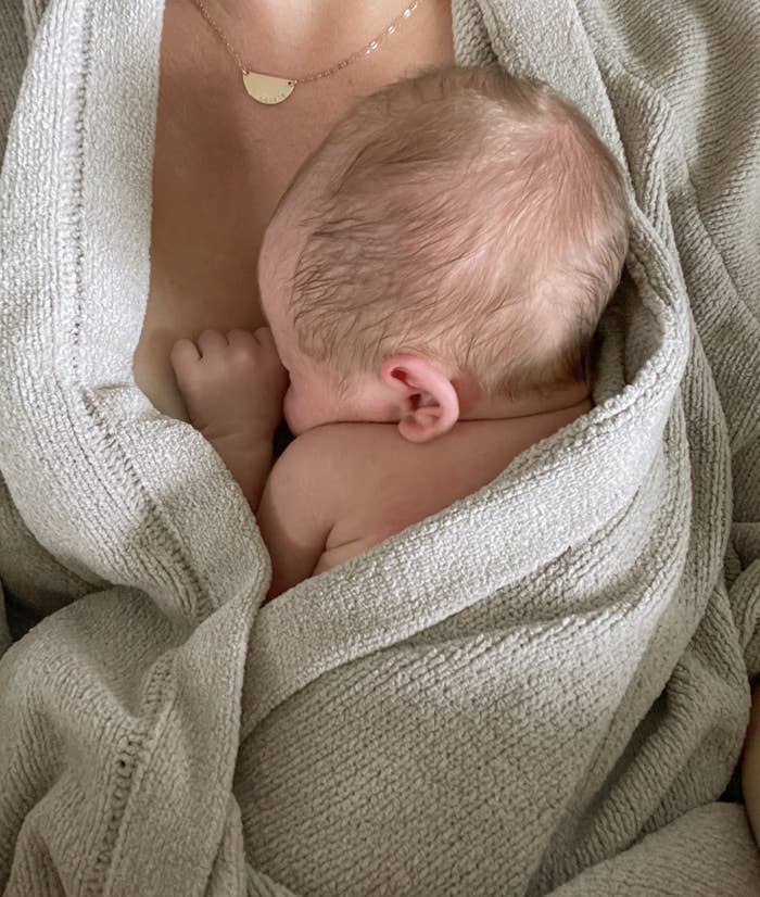An image of a baby&#x27;s head snuggled up on momma&#x27;s chest with a robe on.