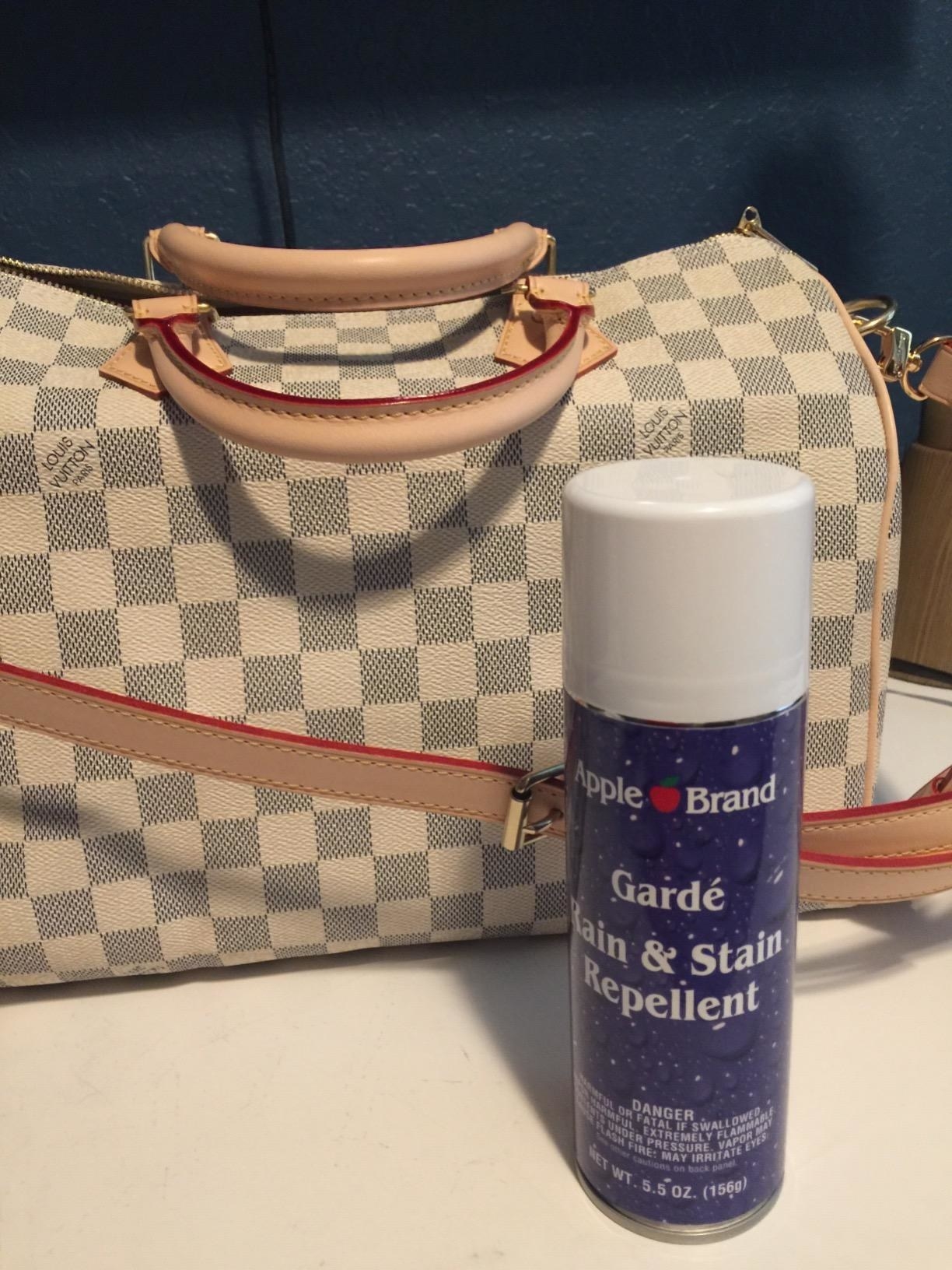 Reviewer photo of the can of repellent sitting next to a Louis Vuitton purse