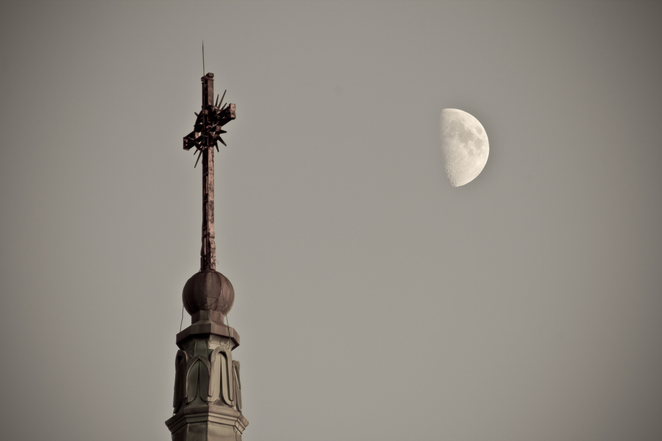 a church steeple angled next to the half moon in the sky