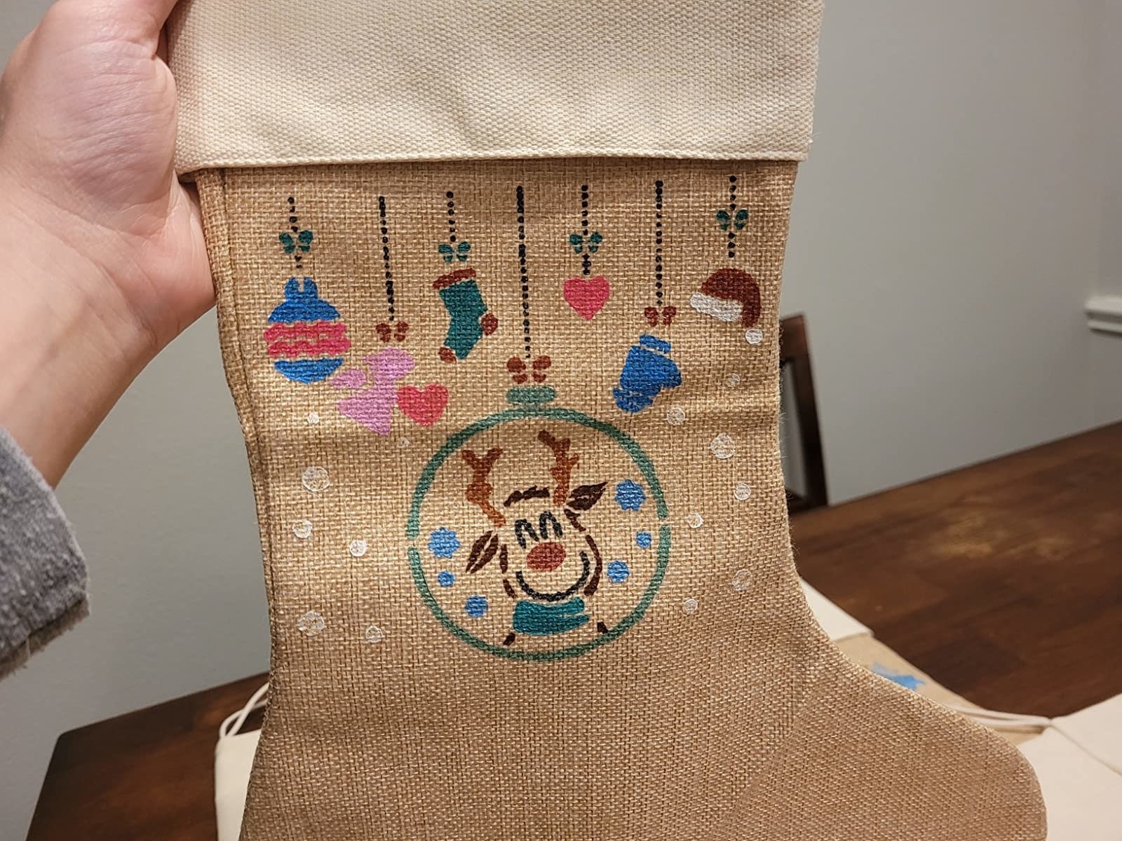 reviewer holds up a painted burlap christmas stocking