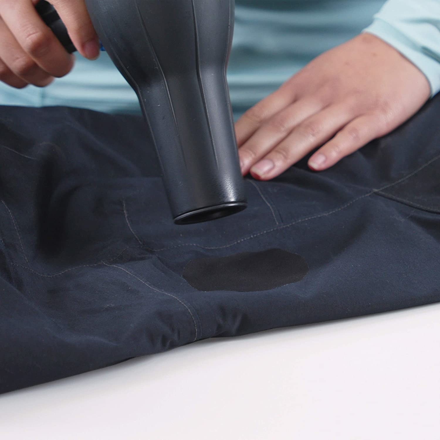A person blow drying a patch onto a jacket