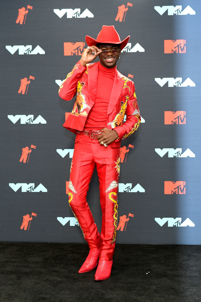 flame-colored cowboy boots, hat, and suit with golden snakes embroidered on the sleeves and pant legs