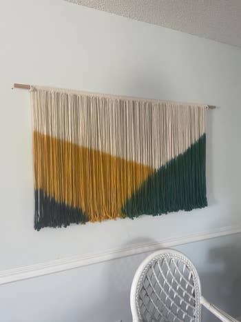 another tapestry with mustard and dark green dyed yarn hanging on a wall