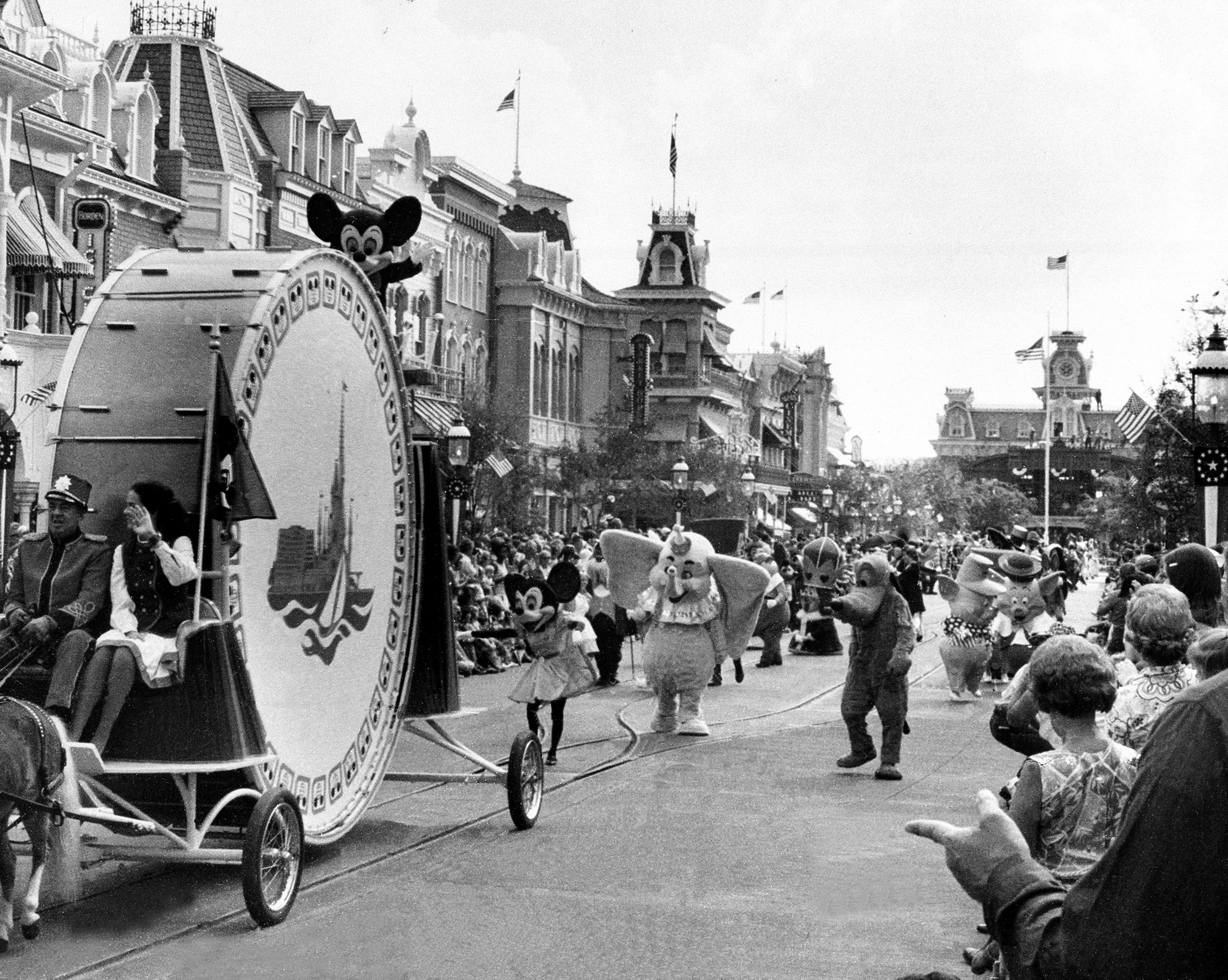 Disney characters are seen walking in a parade for bystanders to celebrate the opening of Disney World