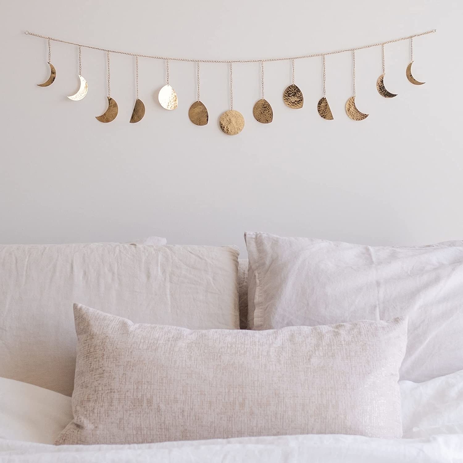 The gold hammered metal moon phase garland above a bed