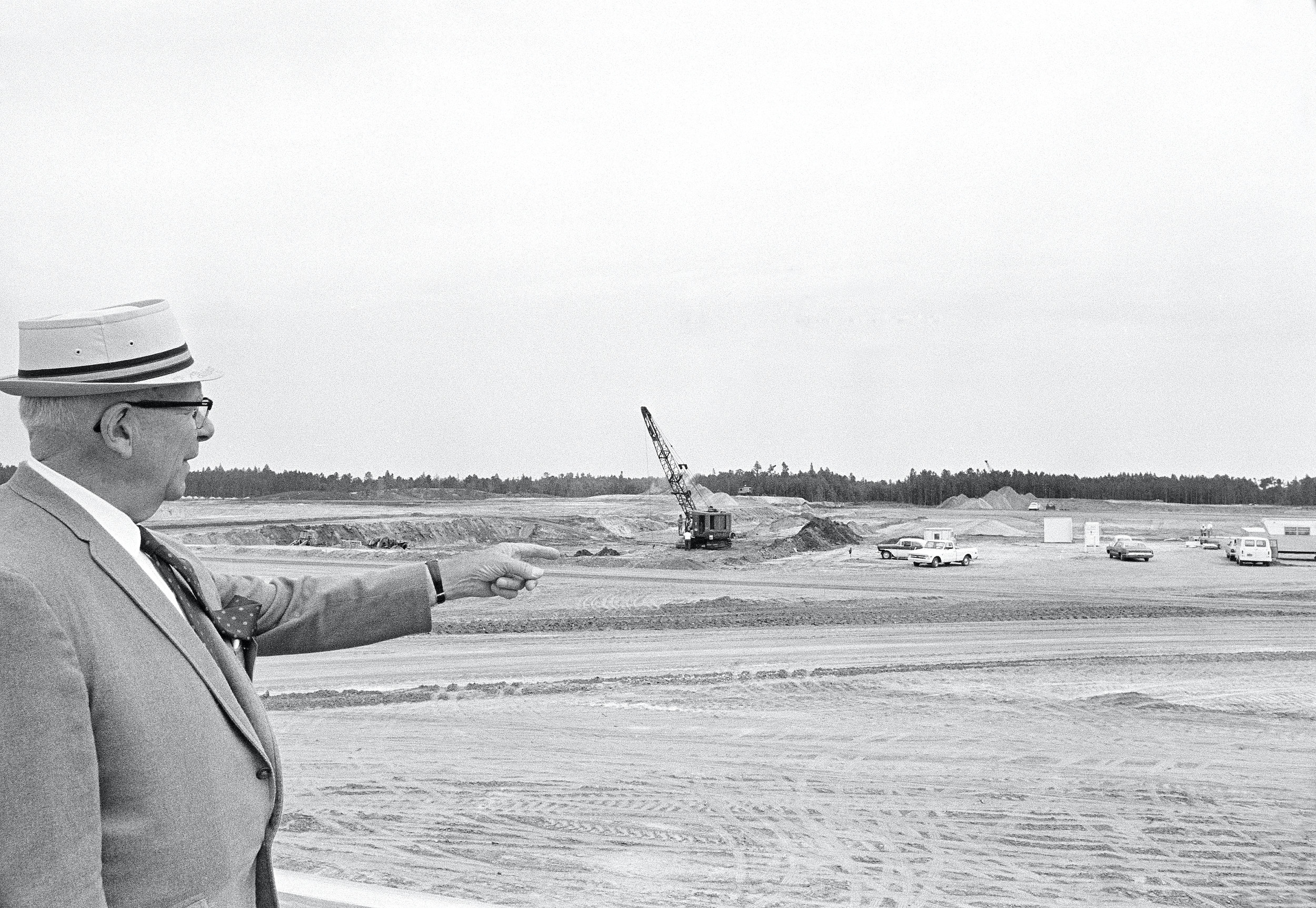 Disney&#x27;s construction manager is seen in a suit pointing towards a field where Disney World would be built