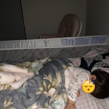 Reviewer's photo of their child sleeping with the bed rail
