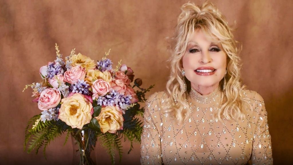 Screen grab of Dolly Parton next to a flower arrangement speaking at the 56th Academy of Country Music Award