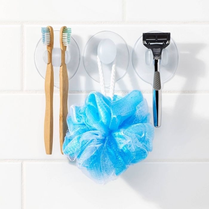 toothbrushes loofah and razor suctioned to shower