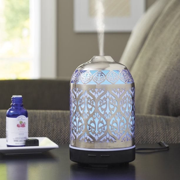 essential oil diffuser with silver filigree design, black base, and blue back light