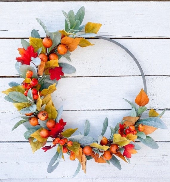a slim wreath with leaves and berries on it