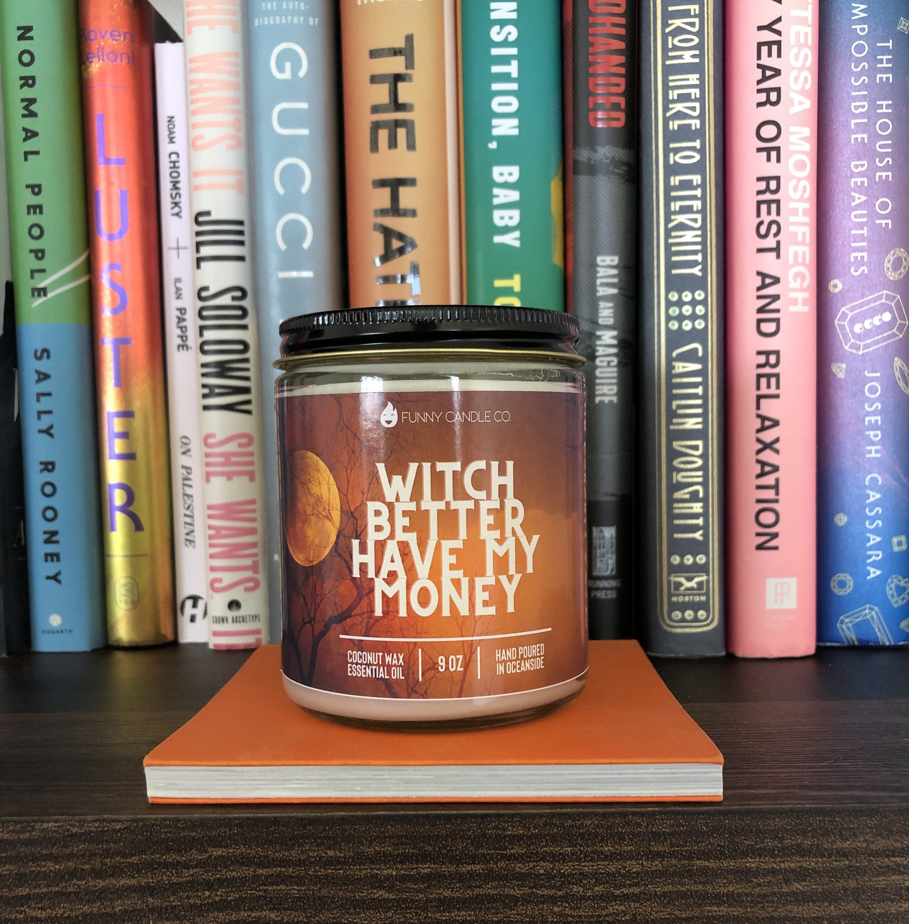 The candle reading "witch better have my money" is displayed on a bookshelf