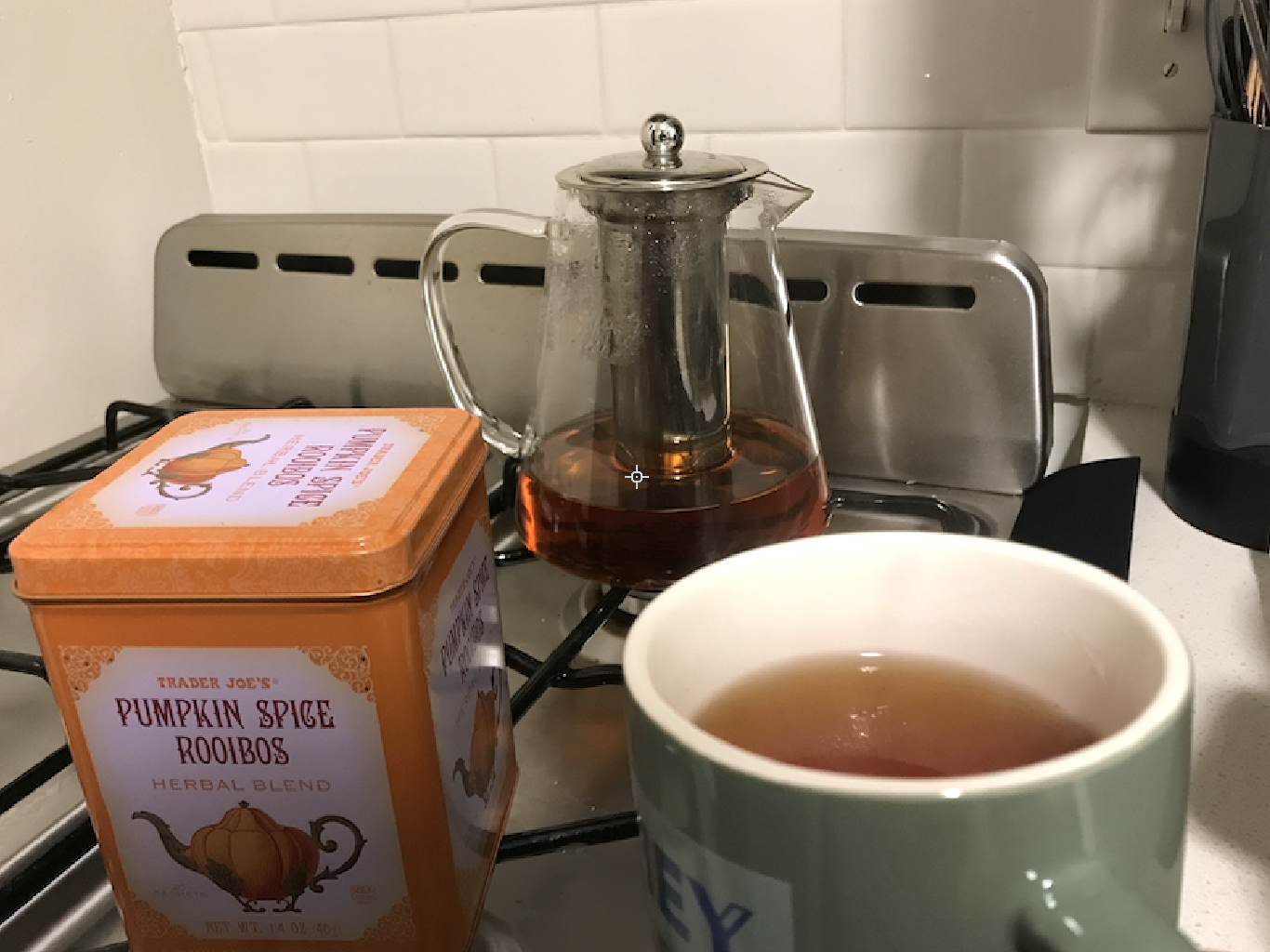 A tea pot with tea in it, the pumpkin spice rooibos container, and a mug of tea