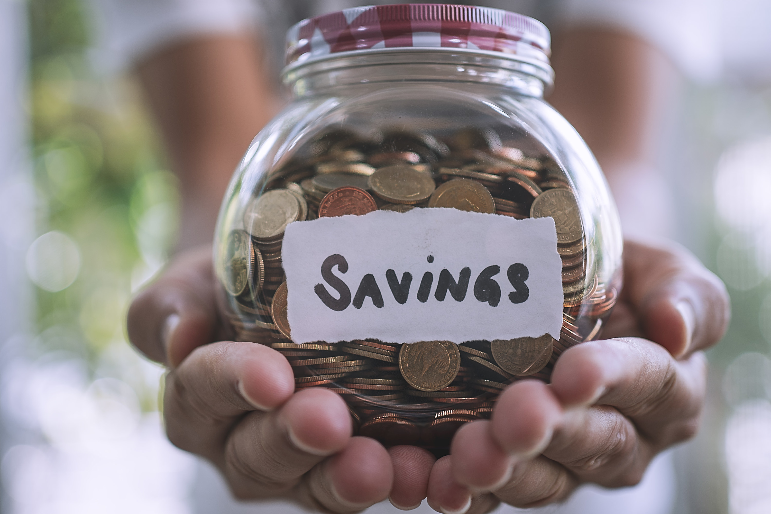 Person holding a jar of coins labeled savings