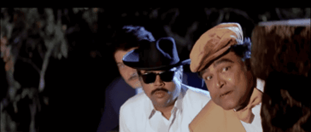 GIF of Amar and Prem riding a cycle/motorcycle as the 3 villains spy on them