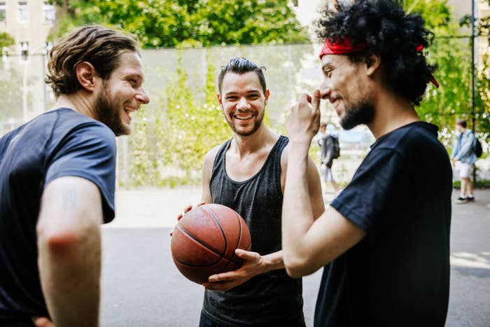 Three guys laughing on a basketball court