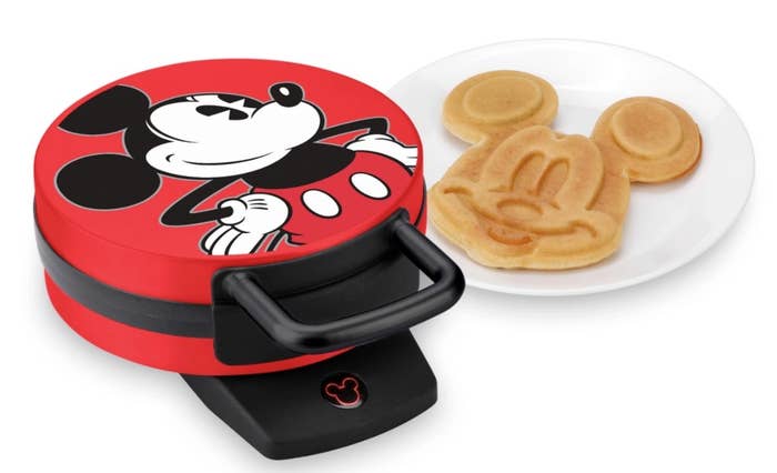 A Mickey-shaped waffle maker with red outside and Mickey image