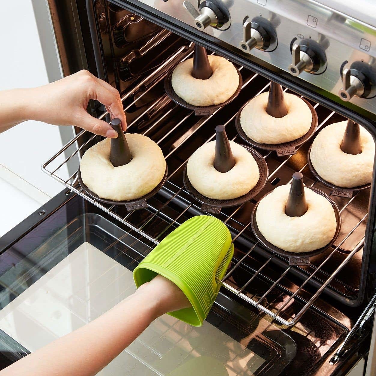 A person placing a bunch of bagels in the oven