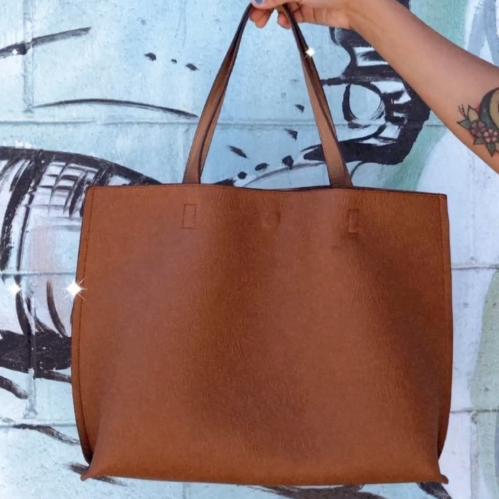 A person carrying a large tote bag over their shoulder