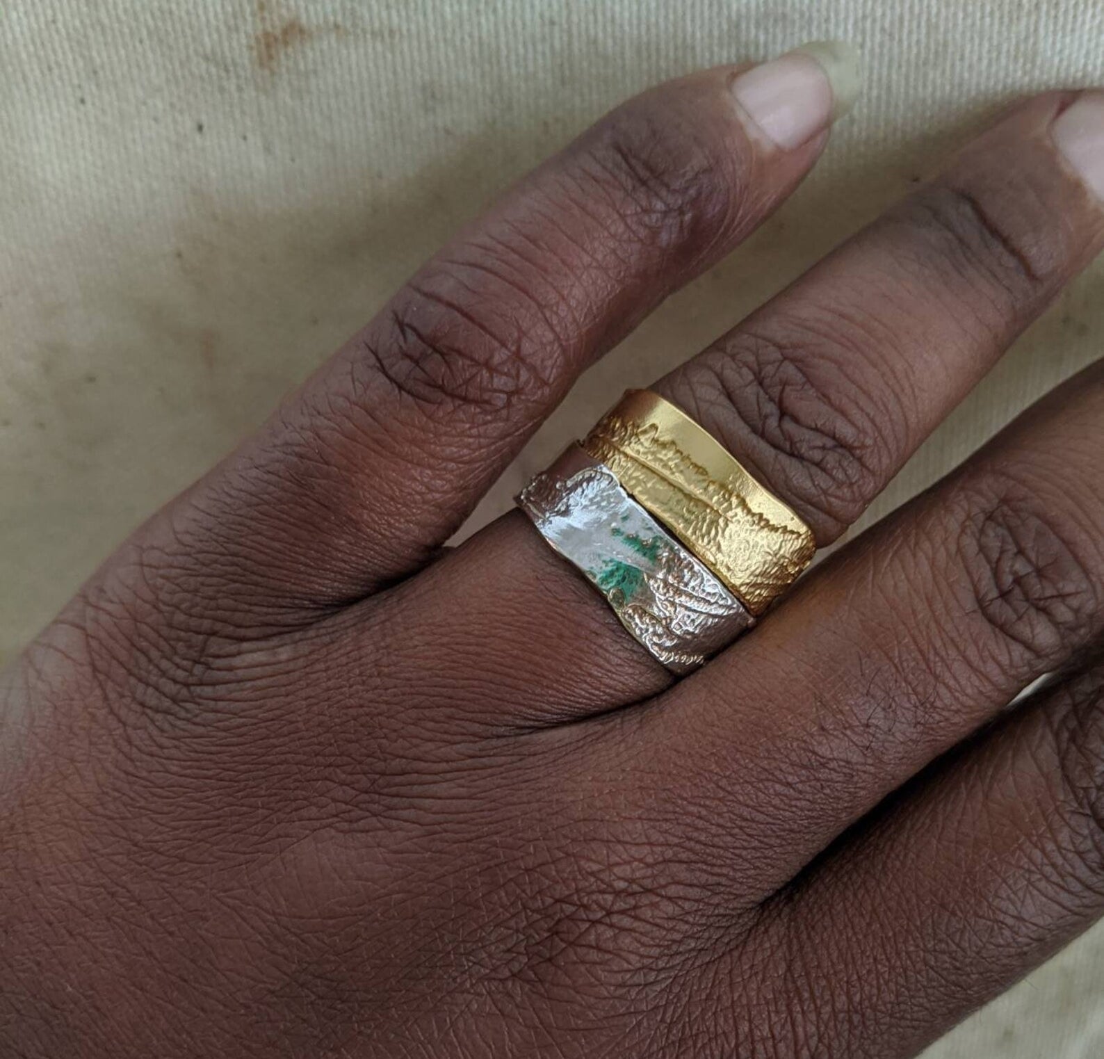 the ring in gold and silver stacked on one finger. both are flat and etched.