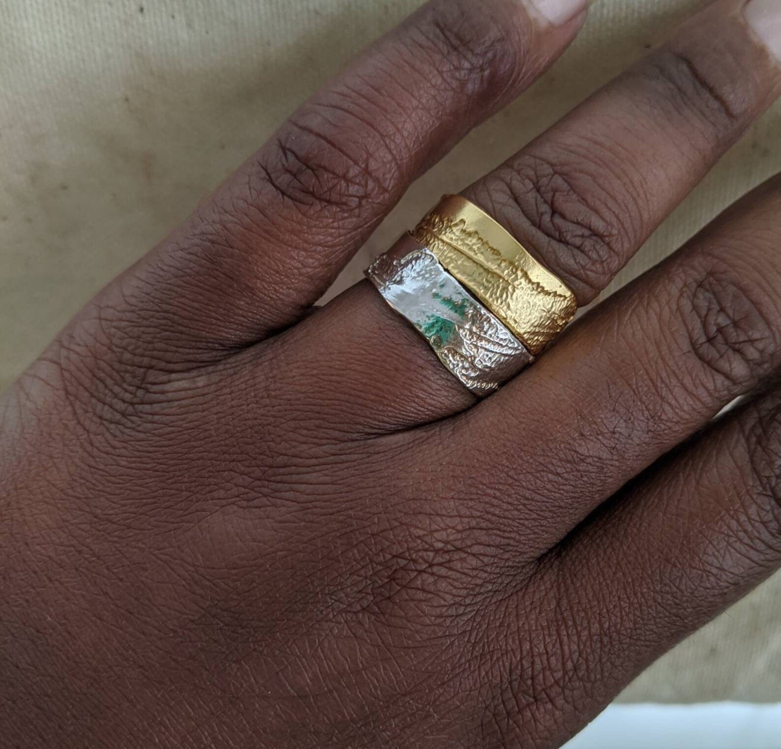 the ring in gold and silver stacked on one finger. both are flat and etched.