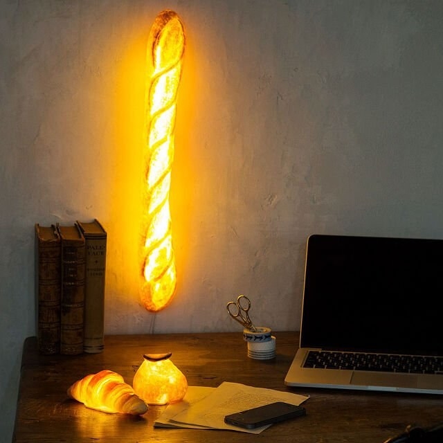 a glowing baguette, croissant, and dinner roll lamp on a home office desk