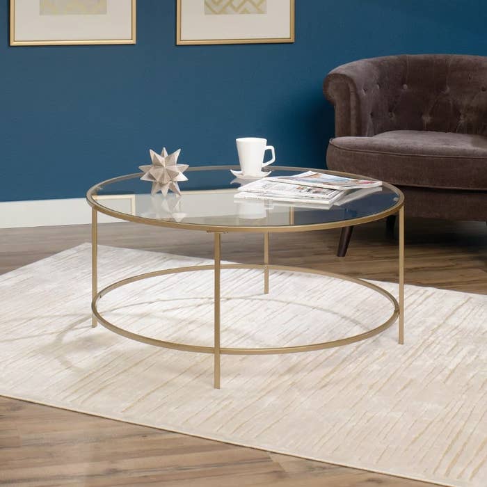 A satin gold/glass, round coffee table in a living room