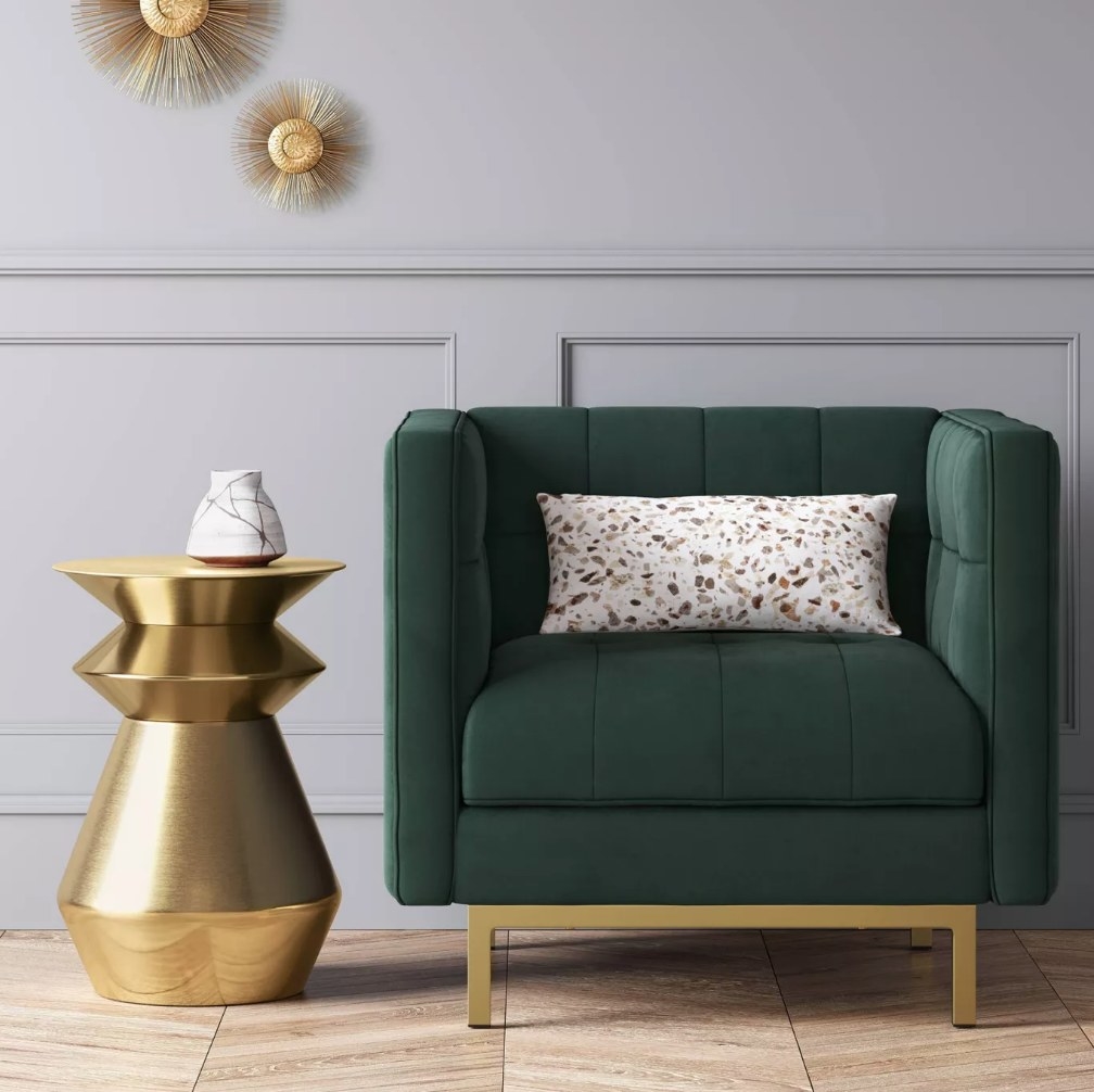 A brass, drum accent table aside an accent chair