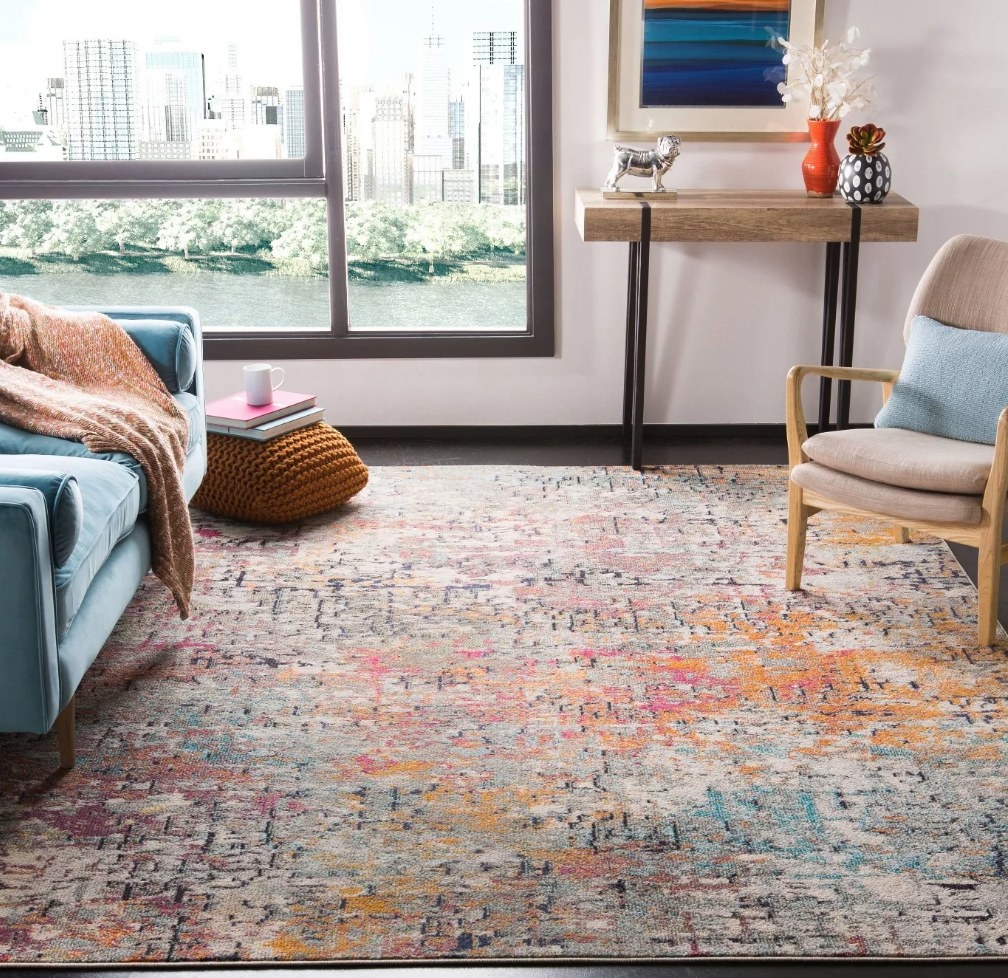 A gray/orange/pink/blue, rectangular area rug in a living room
