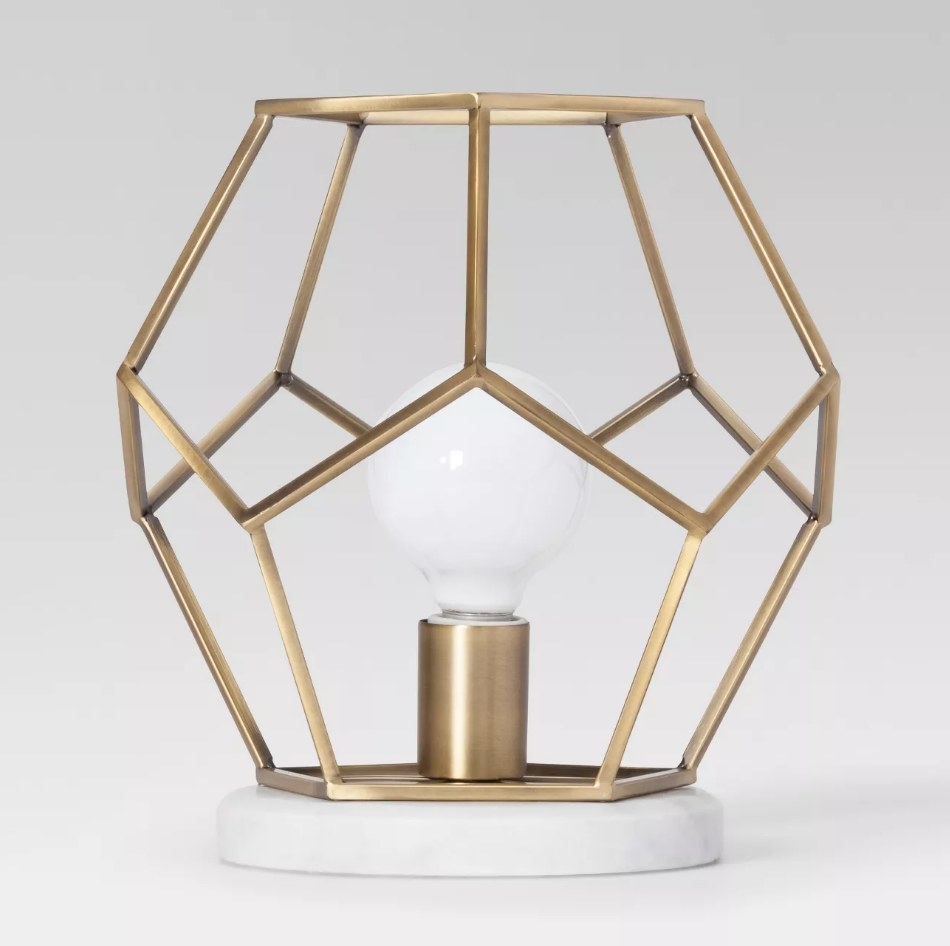 A brass, geometric accent lamp with a marble base