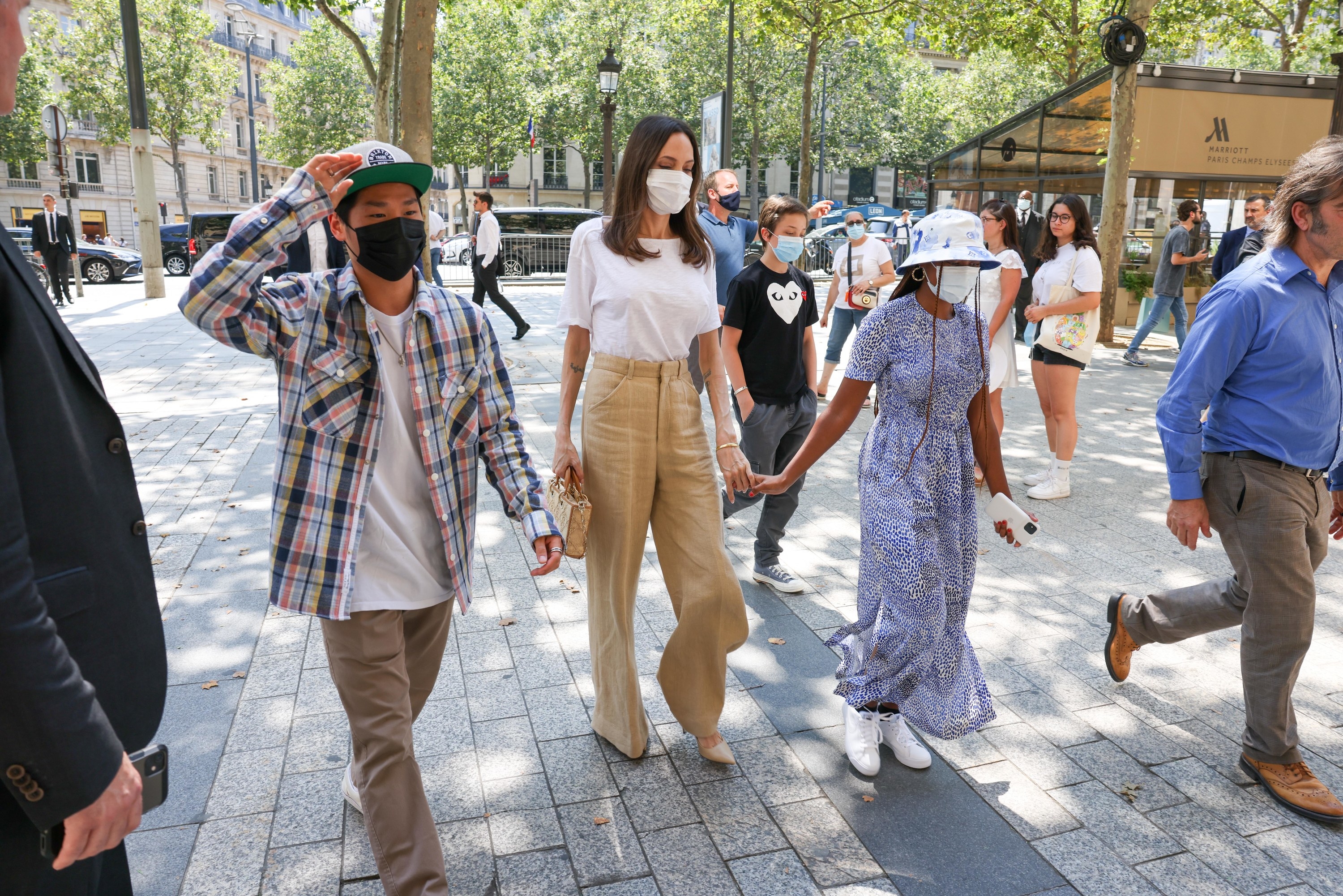 Angelina wearing a mask and holding hands with two of her children, also masked