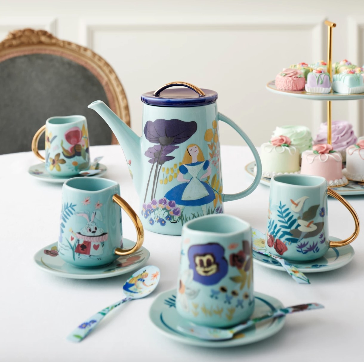 Four blue teacups and saucers with gold handles and Alice in Wonderland decoration