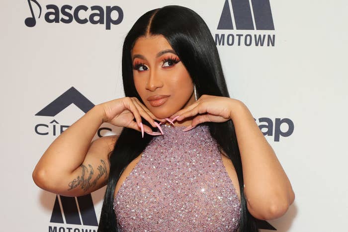 Cardi B posing on a red carpet in a sparkly halter dress