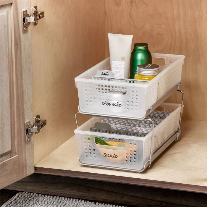 The two-tier organizer placed in a cabinet with assorted items inside