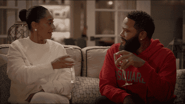 GIF of Rainbow and Andre from Black-ish clilnking wine glasses