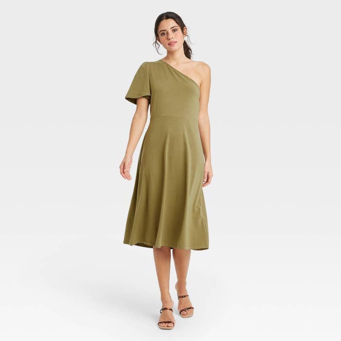 A model wearing an olive green one shoulder dress