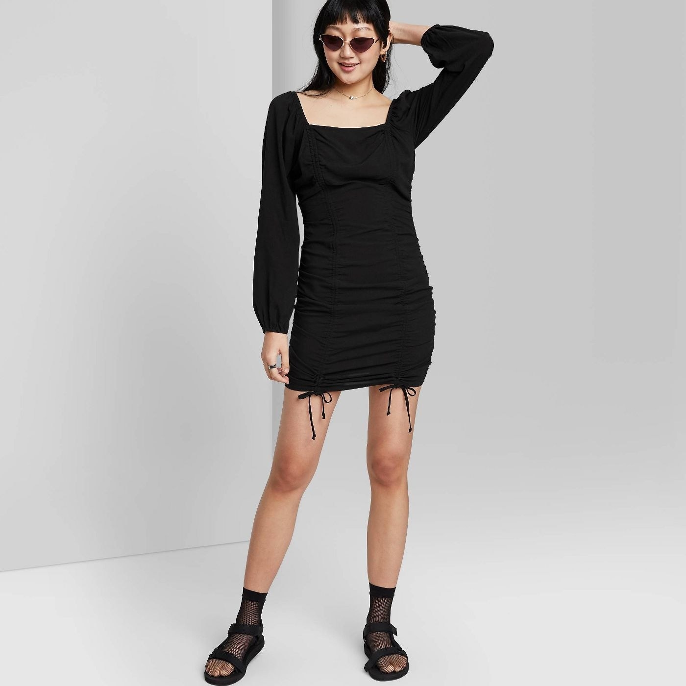 A model waarin a double ruched long puff sleeve black dress