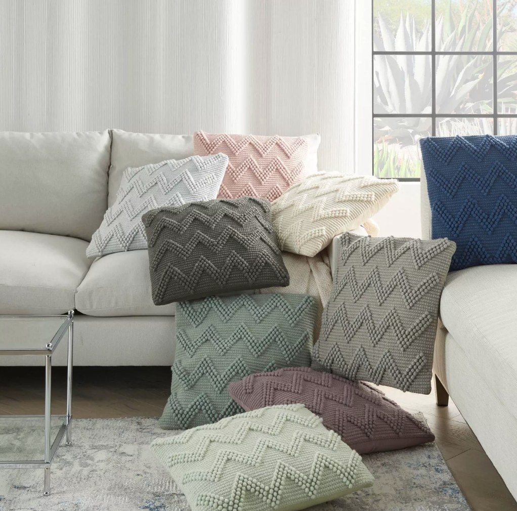 A variety of chevron throw pillows in different colors on a sofa and rug in a living room