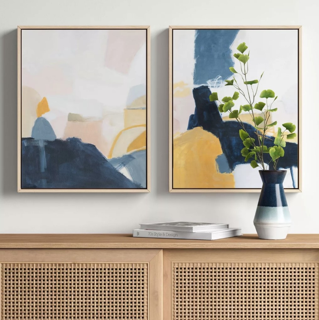 the two abstract canvas prints side by side featuring colors like gray, tan, white and mustard