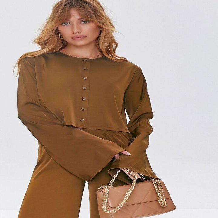 a model wearing a brown button down top with bell sleeves